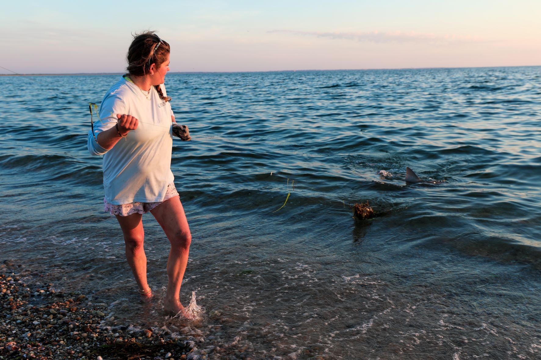 woman on sandy short holding a fishing line