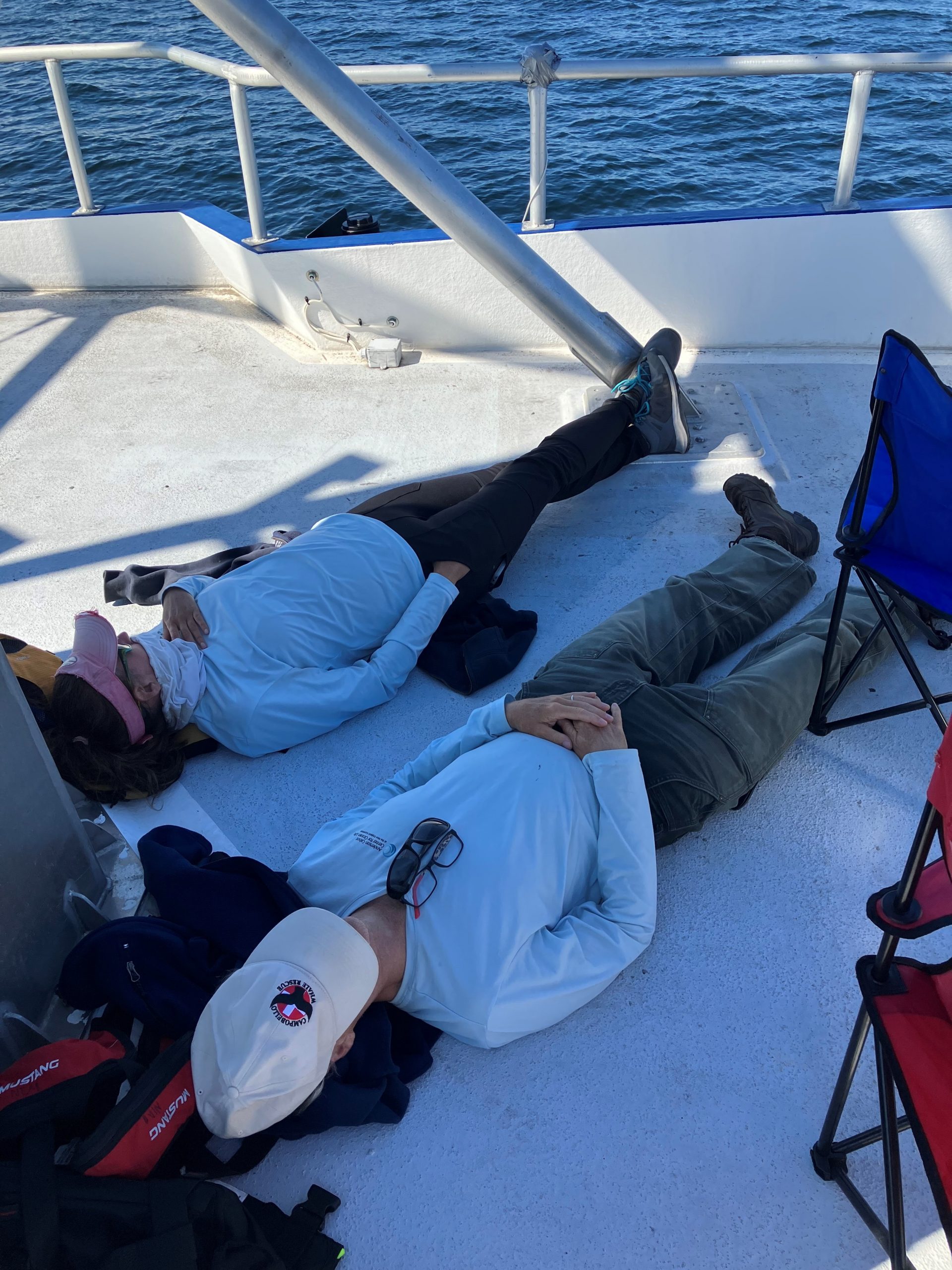 two people sleeping on the deck of a boat
