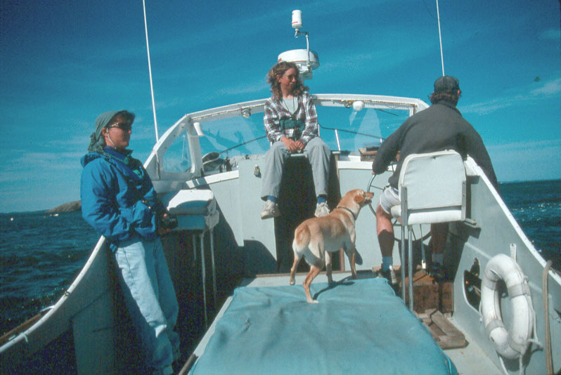 three people and a dog on a small boat