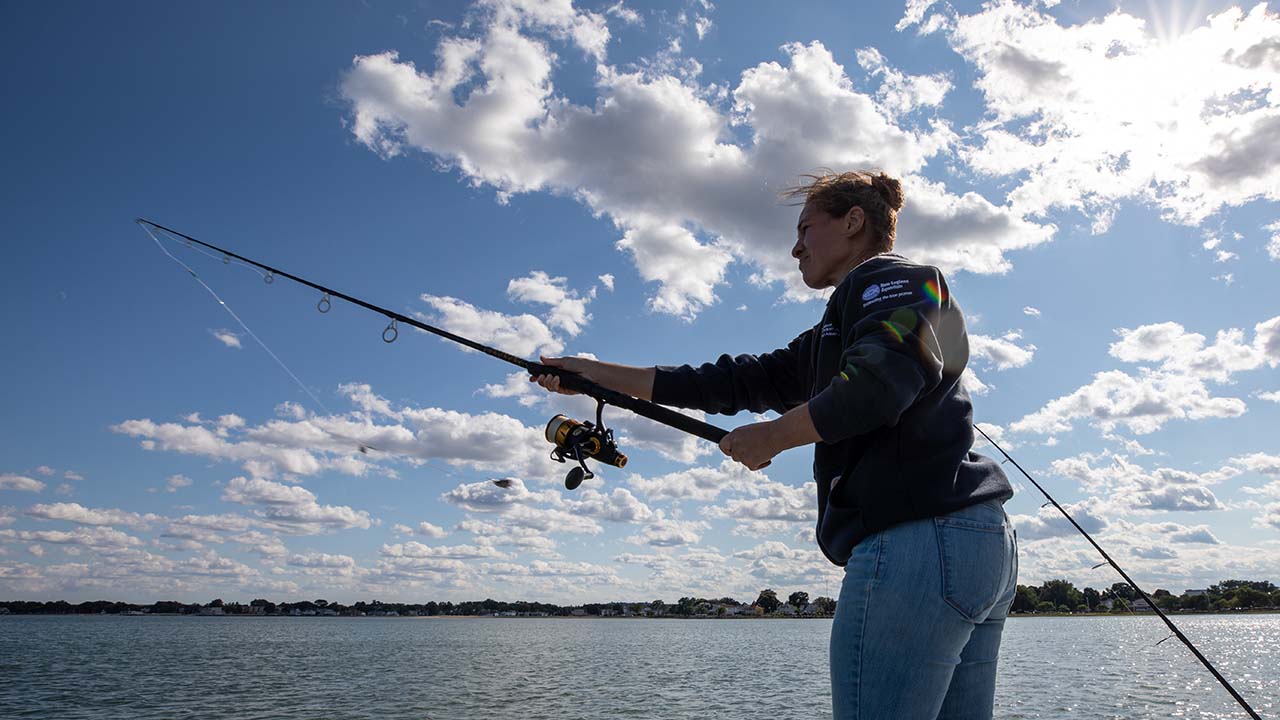 A person using a fishing pole off the side of a boat on a sunny day